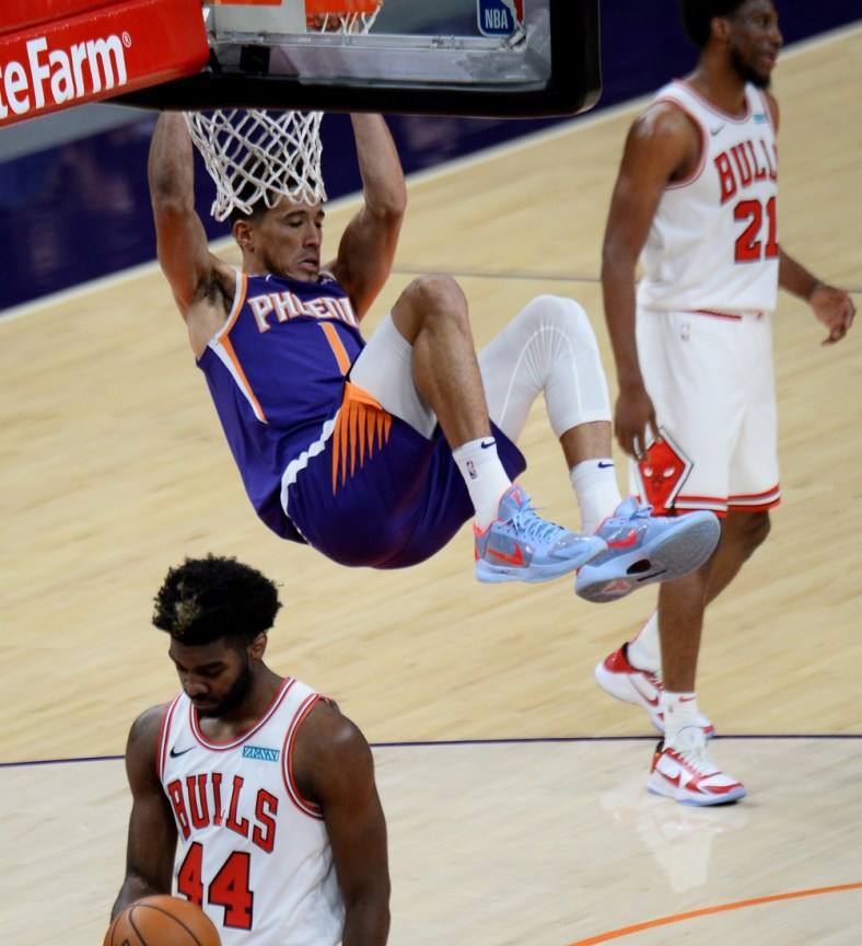 Mar 31, 2021; Phoenix, Arizona, USA; Phoenix Suns guard Devin Booker (1) hangs on the rim after dunking the ball during the first half against the Chicago Bulls at Phoenix Suns Arena. Mandatory Credit: Joe Camporeale-USA TODAY Sports