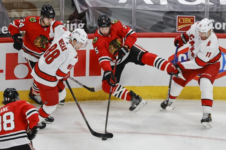 Apr 1, 2021; Chicago, Illinois, USA; Chicago Blackhawks defenseman Connor Murphy (5) battles for the puck with Carolina Hurricanes center Martin Necas (88) in the first period at United Center. Mandatory Credit: Kamil Krzaczynski-USA TODAY Sports