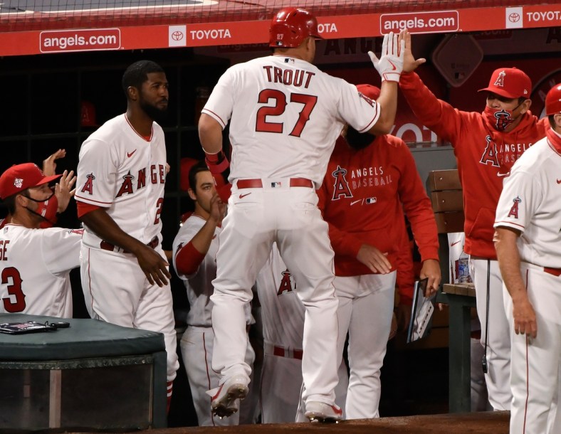 Apr 1, 2021; Anaheim, California, USA; Los Angeles Angels center fielder Mike Trout (27) is greeted at the dugout after scoring on a single by left fielder Justin Upton (not pictured) in the fourth inning against the Chicago White Sox at Angel Stadium. Mandatory Credit: Robert Hanashiro-USA TODAY Sports