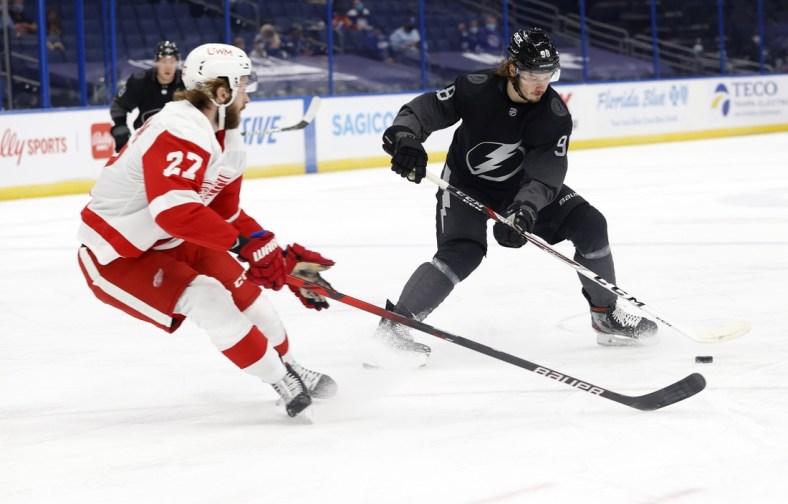 Apr 3, 2021; Tampa, Florida, USA; Tampa Bay Lightning defenseman Mikhail Sergachev (98) skates with the puck as Detroit Red Wings center Michael Rasmussen (27) defends during the first period at Amalie Arena. Mandatory Credit: Kim Klement-USA TODAY Sports