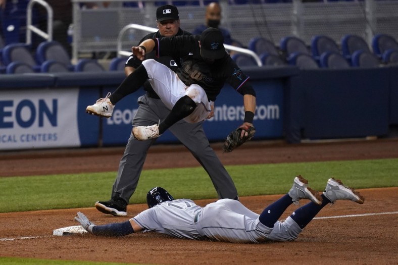 Apr 3, 2021; Miami, Florida, USA; Miami Marlins third baseman Jon Berti (5) leaps over Tampa Bay Rays right fielder Austin Meadows (17) as he steals third base safely in the 3rd inning at loanDepot park. Mandatory Credit: Jasen Vinlove-USA TODAY Sports