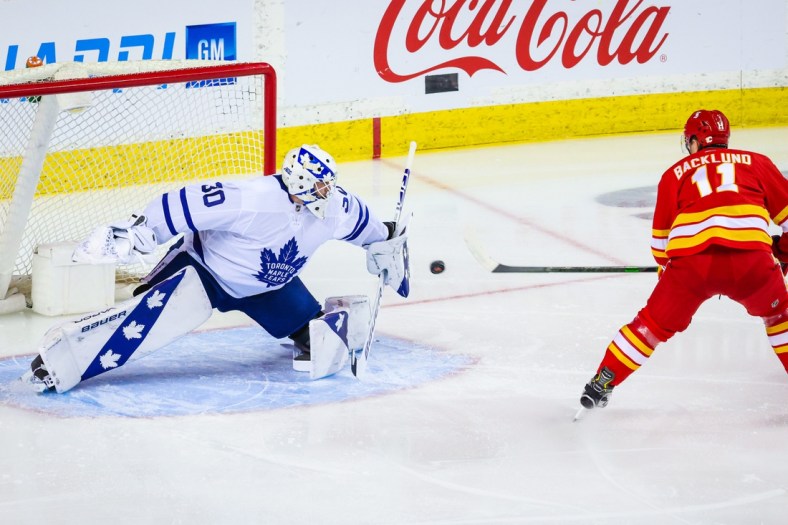 Apr 4, 2021; Calgary, Alberta, CAN; Toronto Maple Leafs goaltender Michael Hutchinson (30) makes a save against Calgary Flames center Mikael Backlund (11) during the first period at Scotiabank Saddledome. Mandatory Credit: Sergei Belski-USA TODAY Sports