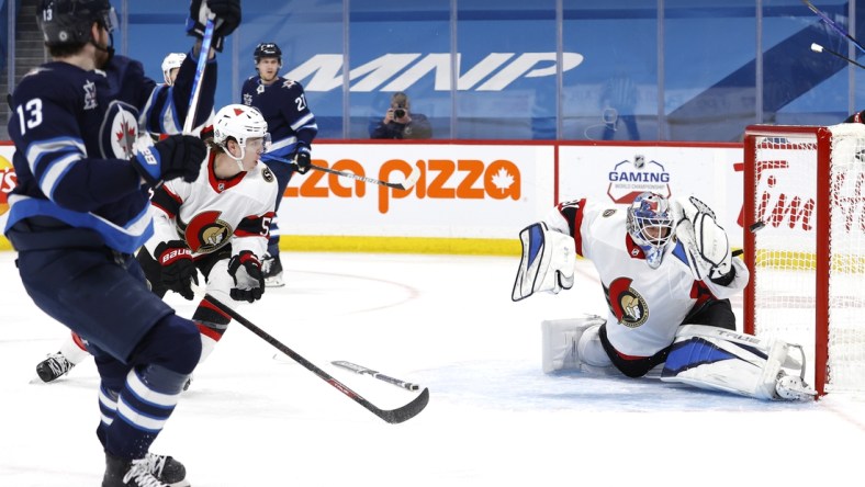 Apr 5, 2021; Winnipeg, Manitoba, CAN;  Winnipeg Jets left wing Pierre-Luc Dubois (13) scores on Ottawa Senators goaltender Anton Forsberg (31) in the second period at Bell MTS Place. Mandatory Credit: James Carey Lauder-USA TODAY Sports