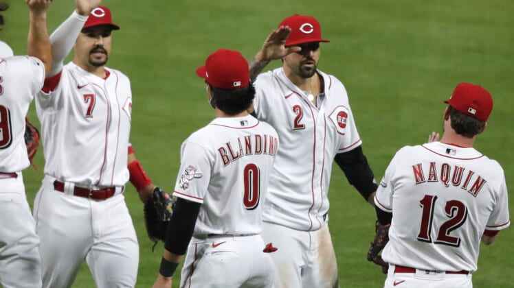 Apr 5, 2021; Cincinnati, Ohio, USA; Cincinnati Reds left fielder Nick Castellanos (2) and shortstop  Eugenio Suarez (7) react with left fielder Tyler Naquin (12) and infielder Alex Blandino (0) after the Reds defeated the Pittsburgh Pirates at Great American Ball Park. Mandatory Credit: David Kohl-USA TODAY Sports
