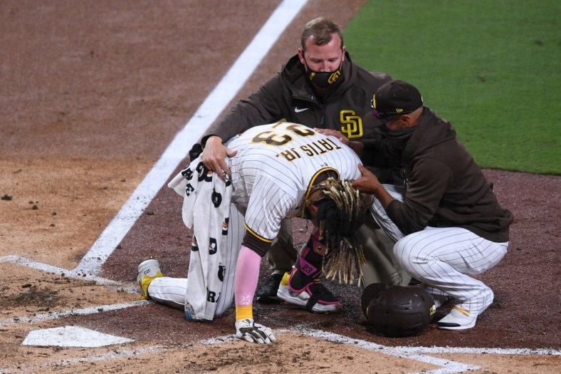 Apr 5, 2021; San Diego, California, USA; San Diego Padres shortstop Fernando Tatis Jr. (23) is looked at by a trainer after injuring himself during a swing as manager Jayce Tingler (R) assists during the third inning against the San Francisco Giants at Petco Park. Mandatory Credit: Orlando Ramirez-USA TODAY Sports