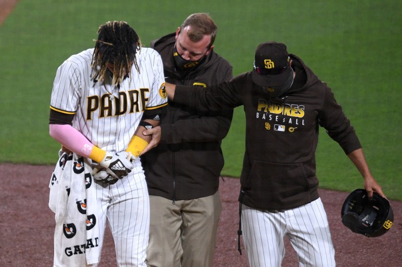 Apr 5, 2021; San Diego, California, USA; San Diego Padres shortstop Fernando Tatis Jr. (L) is helped off the field by a trainer and manager Jayce Tingler (R) after injuring himself during a swing during the third inning against the San Francisco Giants at Petco Park. Mandatory Credit: Orlando Ramirez-USA TODAY Sports