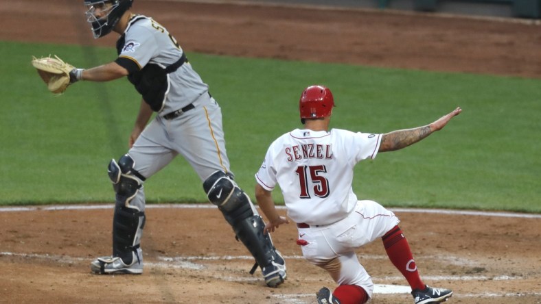 Apr 6, 2021; Cincinnati, Ohio, USA; Cincinnati Reds center fielder Nick Senzel (15) scores against Pittsburgh Pirates catcher Jacob Stallings (58) during the fourth inning at Great American Ball Park. Mandatory Credit: David Kohl-USA TODAY Sports