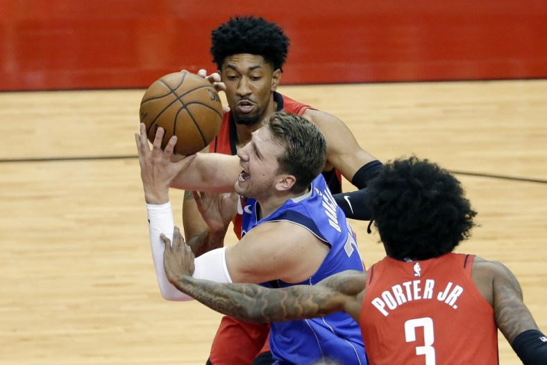 Apr 7, 2021; Houston, Texas, USA;  Dallas Mavericks guard Luka Doncic (77) is fouled as he drives to the basket between during the first half of an NBA basketball game at Toyota Center. Mandatory Credit:  Michael Wyke/POOL PHOTOS-USA TODAY Sports