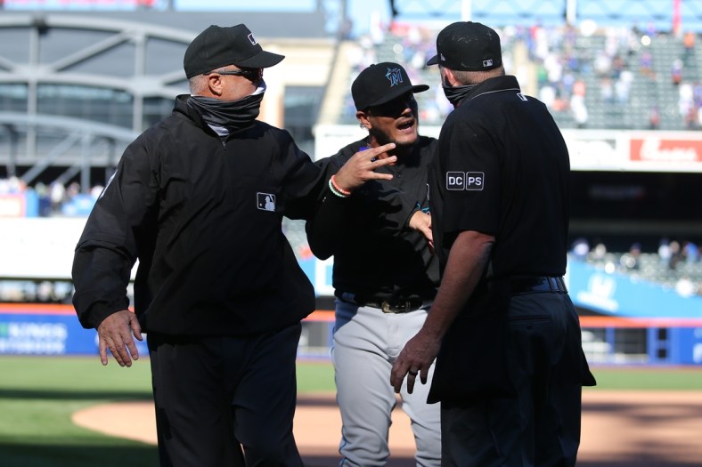 Apr 8, 2021; New York City, New York, USA; Miami Marlins shortstop Miguel Rojas (19) argues with home plate umpire Ron Kulpa (right) and first base umpire Brian O'Nora (left) after losing to the New York Mets on a hit by pitch during an opening day game at Citi Field. Mandatory Credit: Brad Penner-USA TODAY Sports