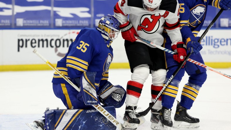 Apr 8, 2021; Buffalo, New York, USA; New Jersey Devils left wing Miles Wood (44) tries to deflect a shot on Buffalo Sabres goaltender Linus Ullmark (35) during the first period at KeyBank Center. Mandatory Credit: Timothy T. Ludwig-USA TODAY Sports