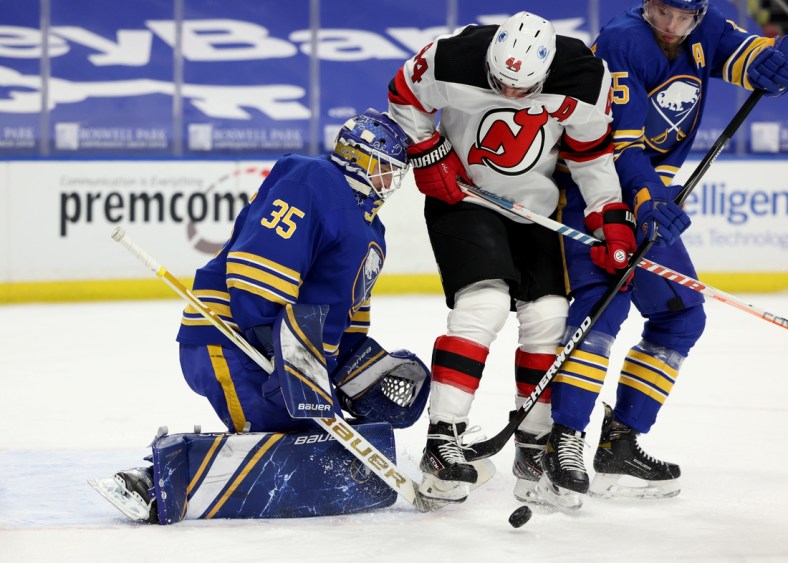Apr 8, 2021; Buffalo, New York, USA; New Jersey Devils left wing Miles Wood (44) tries to deflect a shot on Buffalo Sabres goaltender Linus Ullmark (35) during the first period at KeyBank Center. Mandatory Credit: Timothy T. Ludwig-USA TODAY Sports