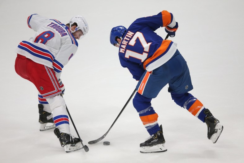 Apr 9, 2021; Uniondale, New York, USA; New York Rangers defenseman Jacob Trouba (8) and New York Islanders left wing Matt Martin (17) fight for the puck during the first period at Nassau Veterans Memorial Coliseum. Mandatory Credit: Brad Penner-USA TODAY Sports