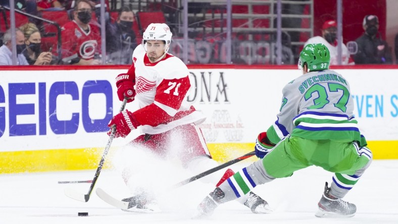 Apr 10, 2021; Raleigh, North Carolina, USA;  Detroit Red Wings center Dylan Larkin (71) tries to control the puck against Carolina Hurricanes right wing Andrei Svechnikov (37) at PNC Arena. Mandatory Credit: James Guillory-USA TODAY Sports