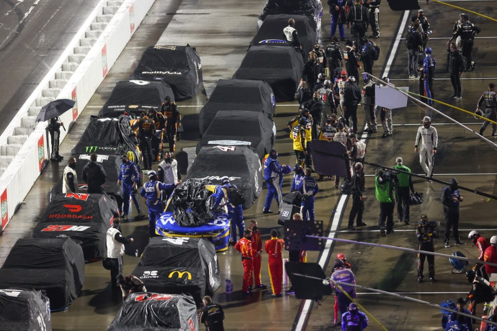 Apr 10, 2021; Martinsville, Virginia, USA; NASCAR Cup Series pit crews cover cars during a rain delay during the Blue-Emu Maximum Pain Relief 500 at Martinsville Speedway. Mandatory Credit: Ryan Hunt-USA TODAY Sports
