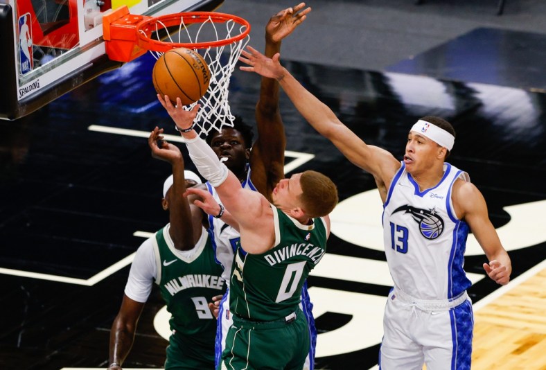 Apr 11, 2021; Orlando, Florida, USA;  Milwaukee Bucks guard Donte DiVincenzo (0) drives the the hoop over Orlando Magic guard R.J. Hampton (13) in the second quarter at Amway Center. Mandatory Credit: Nathan Ray Seebeck-USA TODAY Sports