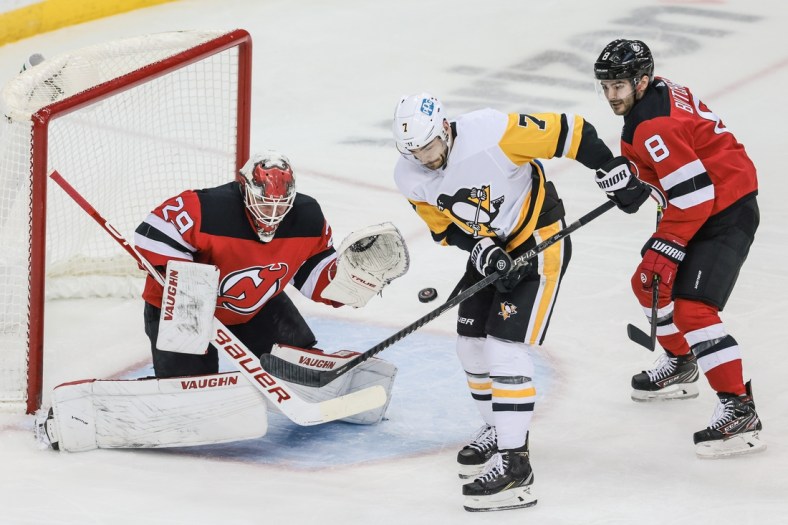 Apr 11, 2021; Newark, New Jersey, USA; Pittsburgh Penguins center Colton Sceviour (7) deflects a shot in front of New Jersey Devils goaltender Mackenzie Blackwood (29) and defenseman Will Butcher (8) during the second period at Prudential Center. Mandatory Credit: Vincent Carchietta-USA TODAY Sports