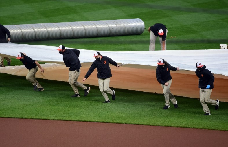 Apr 12, 2021; Baltimore, Maryland, USA; Members of the grounds crew put the tarp on the field prior to a game between the Seattle Mariners and Baltimore Orioles at Oriole Park at Camden Yards. Mandatory Credit: Evan Habeeb-USA TODAY Sports