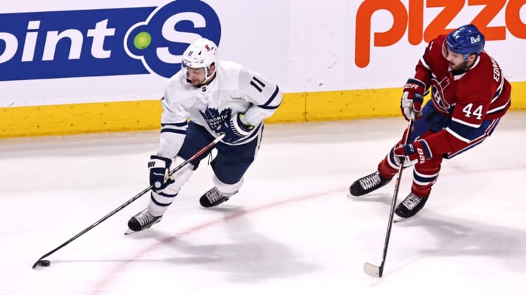 Apr 12, 2021; Montreal, Quebec, CAN; Toronto Maple Leafs left wing Zach Hyman (11) plays the puck against Montreal Canadiens defenseman Joel Edmundson (44) during the first period at Bell Centre. Mandatory Credit: Jean-Yves Ahern-USA TODAY Sports