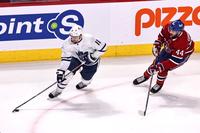 Apr 12, 2021; Montreal, Quebec, CAN; Toronto Maple Leafs left wing Zach Hyman (11) plays the puck against Montreal Canadiens defenseman Joel Edmundson (44) during the first period at Bell Centre. Mandatory Credit: Jean-Yves Ahern-USA TODAY Sports