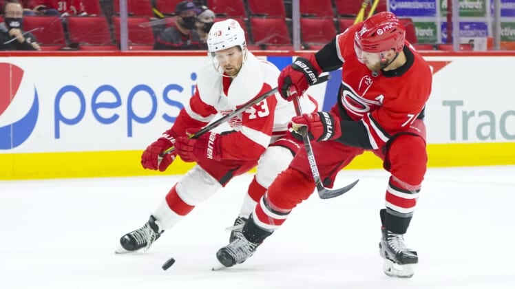 Apr 12, 2021; Raleigh, North Carolina, USA; Carolina Hurricanes defenseman Jaccob Slavin (74) and Detroit Red Wings left wing Darren Helm (43) battle over the puck during the first period at PNC Arena. Mandatory Credit: James Guillory-USA TODAY Sports