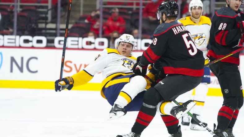 Apr 15, 2021; Raleigh, North Carolina, USA;  Carolina Hurricanes defenseman Jani Hakanpaa (58) checks Nashville Predators center Mikael Granlund (64) during the first period at PNC Arena. Mandatory Credit: James Guillory-USA TODAY Sports