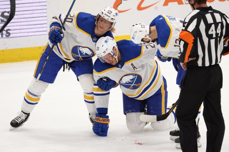 Apr 15, 2021; Washington, District of Columbia, USA; Buffalo Sabres right wing Kyle Okposo (21) is helped to his feet by Sabres center Cody Eakin (20) and Sabres left wing Tobias Rieder (13) after being struck in the face by the puck against the Washington Capitals in the first period at Capital One Arena. Mandatory Credit: Geoff Burke-USA TODAY Sports