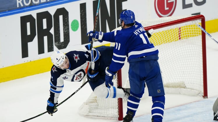 Apr 15, 2021; Toronto, Ontario, CAN; Toronto Maple Leafs forward Zach Hyman (11) knocks Winnipeg Jets defenseman Neal Pionk (4) to the ice during the third period at Scotiabank Arena. Mandatory Credit: John E. Sokolowski-USA TODAY Sports