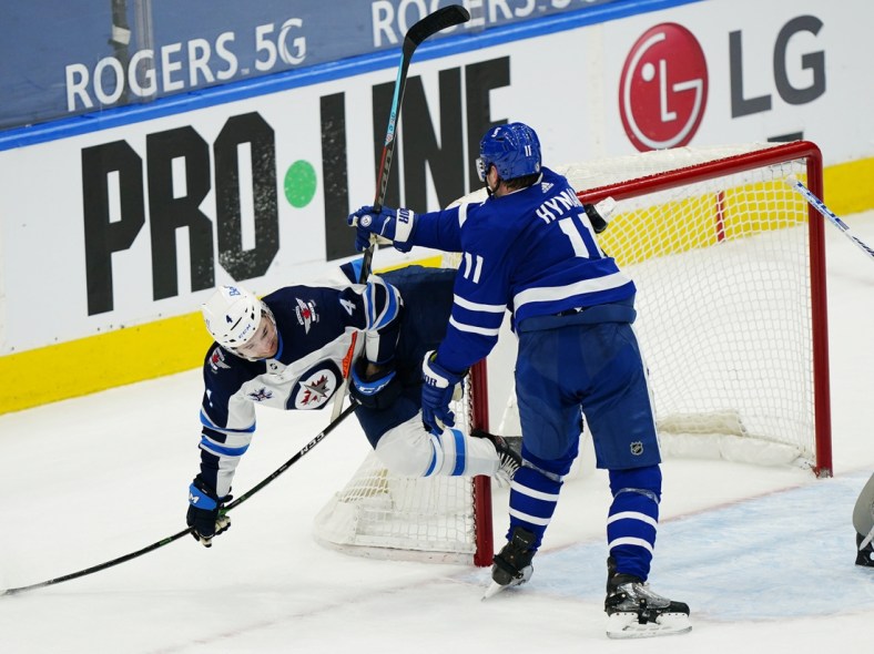 Apr 15, 2021; Toronto, Ontario, CAN; Toronto Maple Leafs forward Zach Hyman (11) knocks Winnipeg Jets defenseman Neal Pionk (4) to the ice during the third period at Scotiabank Arena. Mandatory Credit: John E. Sokolowski-USA TODAY Sports