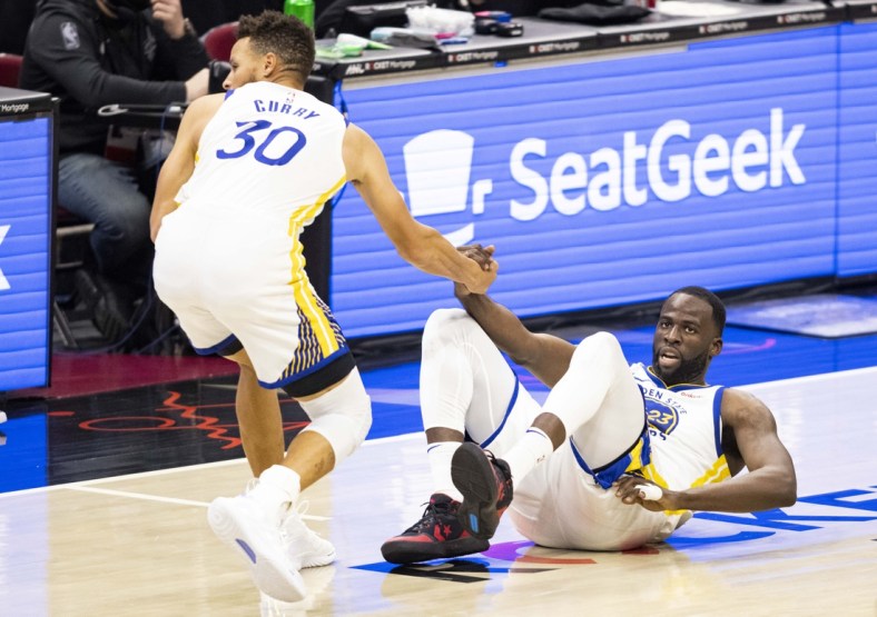 Apr 15, 2021; Cleveland, Ohio, USA; Golden State Warriors guard Stephen Curry (30) helps forward Draymond Green (23) up from the court during the third quarter against the Cleveland Cavaliers at Rocket Mortgage FieldHouse. Mandatory Credit: Scott Galvin-USA TODAY Sports
