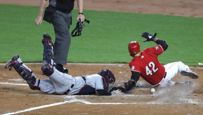 Apr 16, 2021; Cincinnati, Ohio, USA; Cincinnati Reds right fielder Nick Castellanos (right) slides safely into home against Cleveland Indians catcher Roberto Perez (left) during the third inning at Great American Ball Park. Mandatory Credit: David Kohl-USA TODAY Sports