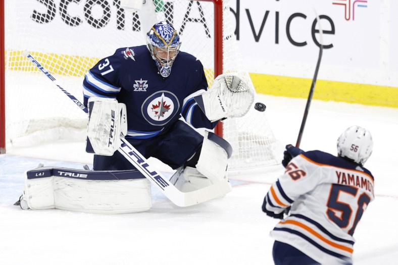 Apr 17, 2021; Winnipeg, Manitoba, CAN; Edmonton Oilers right wing Kailer Yamamoto (56) shoots on Winnipeg Jets goaltender Connor Hellebuyck (37) in the first period at Bell MTS Place. Mandatory Credit: James Carey Lauder-USA TODAY Sports