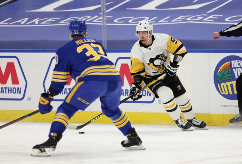 Apr 18, 2021; Buffalo, New York, USA;  Pittsburgh Penguins center Evan Rodrigues (9) controls the puck against Buffalo Sabres defenseman Colin Miller (33) during the first period at KeyBank Center. Mandatory Credit: Timothy T. Ludwig-USA TODAY Sports
