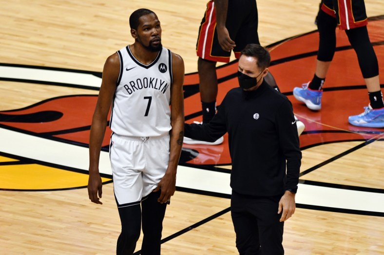 Apr 18, 2021; Miami, Florida, USA; Brooklyn Nets forward Kevin Durant (7) holds his left leg as head coach Steve Nash assists him from the court during the first half of a game against the Miami Heat at American Airlines Arena. Mandatory Credit: Jim Rassol-USA TODAY Sports