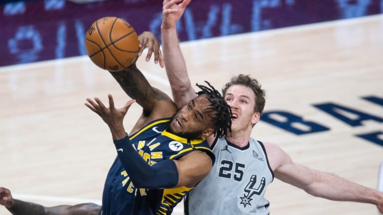 Apr 19, 2021; Indianapolis, Indiana, USA; Indiana Pacers forward Oshae Brissett (12) rebounds the ball over San Antonio Spurs center Jakob Poeltl (25)  in the second quarter at Bankers Life Fieldhouse. Mandatory Credit: Trevor Ruszkowski-USA TODAY Sports