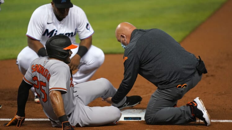Apr 20, 2021; Miami, Florida, USA; Baltimore Orioles right fielder Anthony Santander (25) sits on the field while being attended to by a team trainer after an apparent injury in the 1st against the Miami Marlins at loanDepot park. Mandatory Credit: Jasen Vinlove-USA TODAY Sports