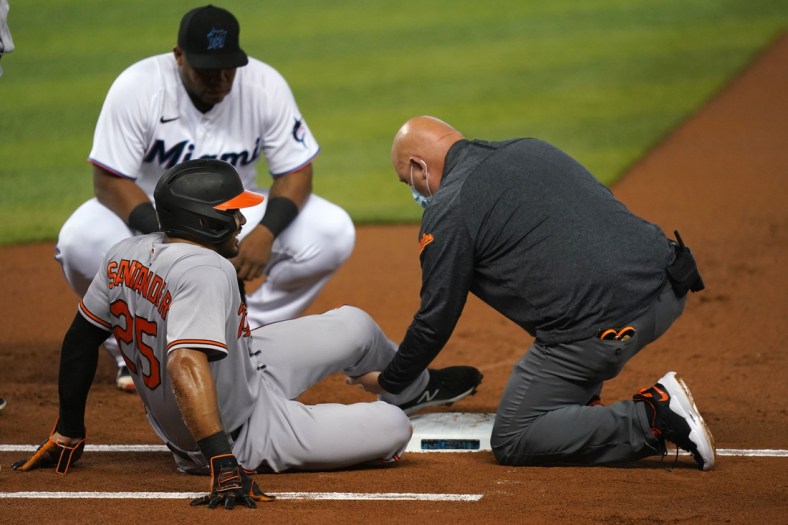 Apr 20, 2021; Miami, Florida, USA; Baltimore Orioles right fielder Anthony Santander (25) sits on the field while being attended to by a team trainer after an apparent injury in the 1st against the Miami Marlins at loanDepot park. Mandatory Credit: Jasen Vinlove-USA TODAY Sports