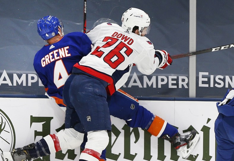 Apr 22, 2021; Uniondale, New York, USA; New York Islanders defenseman Andy Greene (4) is checked into the boards by Washington Capitals center Nic Dowd (26) during the first period at Nassau Veterans Memorial Coliseum. Mandatory Credit: Andy Marlin-USA TODAY Sports