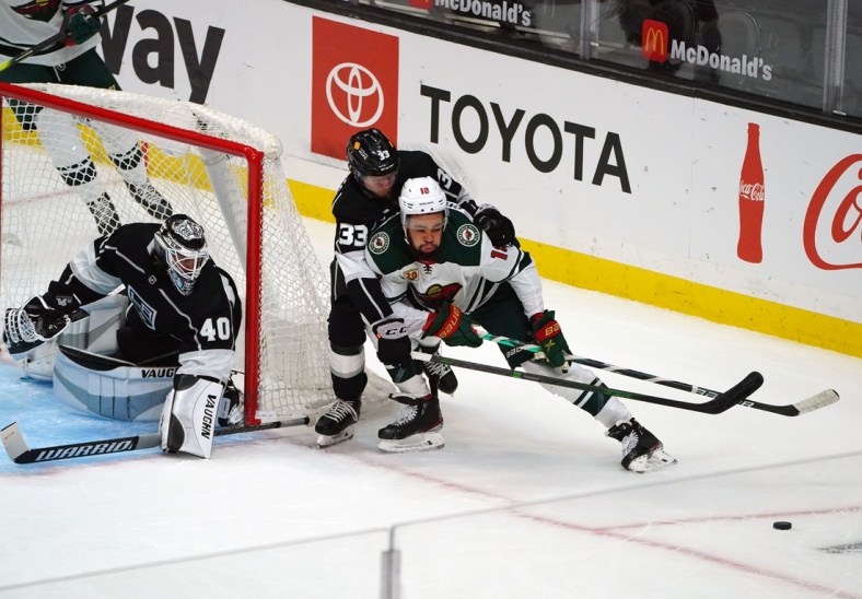 Apr 23, 2021; Los Angeles, California, USA; Minnesota Wild left wing Jordan Greenway (18) moves the puck as Los Angeles Kings defenseman Tobias Bjornfot (33) helps goaltender Calvin Petersen (40) defend the goal during the first period at Staples Center. Mandatory Credit: Gary A. Vasquez-USA TODAY Sports