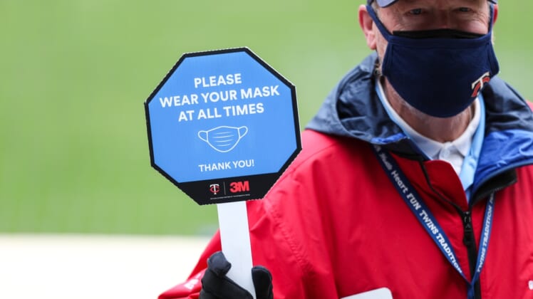 Apr 24, 2021; Minneapolis, Minnesota, USA; A Target Field employee holds a sign reminding fans to wear their mask in the first inning during a game between the Pittsburgh Pirates and Minnesota Twins at Target Field. Mandatory Credit: David Berding-USA TODAY Sports