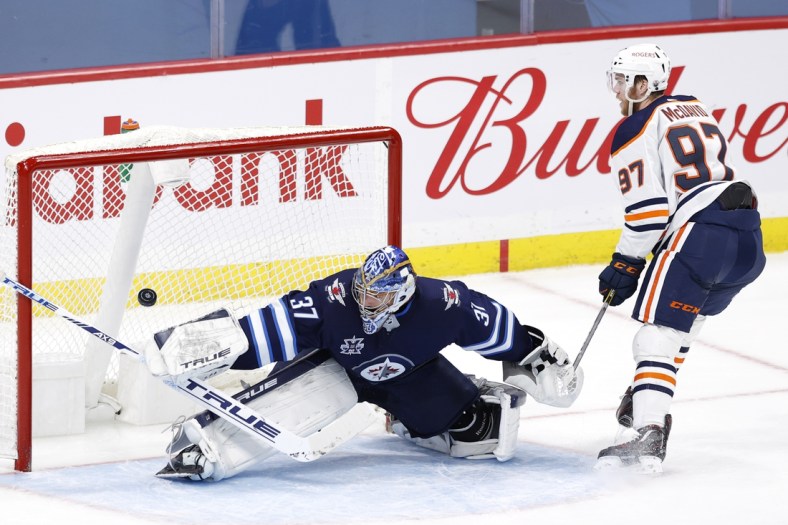 Apr 26, 2021; Winnipeg, Manitoba, CAN; Edmonton Oilers center Connor McDavid (97) scores on Winnipeg Jets goaltender Connor Hellebuyck (37) in the second period at Bell MTS Place. Mandatory Credit: James Carey Lauder-USA TODAY Sports
