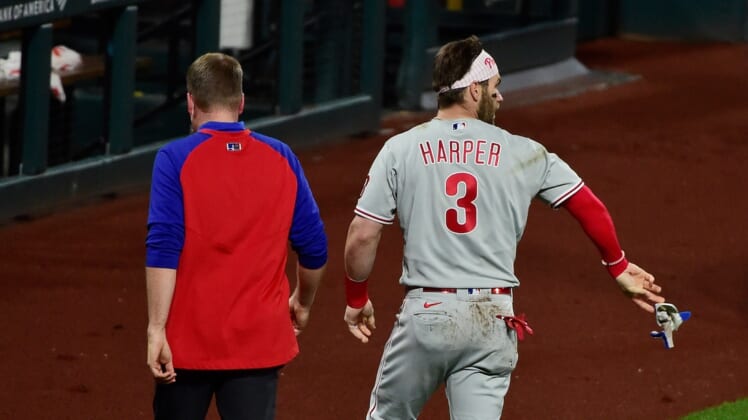 Apr 28, 2021; St. Louis, Missouri, USA;  Philadelphia Phillies right fielder Bryce Harper (3) tosses his batting gloves on the field as he walks off with a trainer after he was hit by a pitch from St. Louis Cardinals relief pitcher Genesis Cabrera (not pictured) during the sixth inning at Busch Stadium. Mandatory Credit: Jeff Curry-USA TODAY Sports
