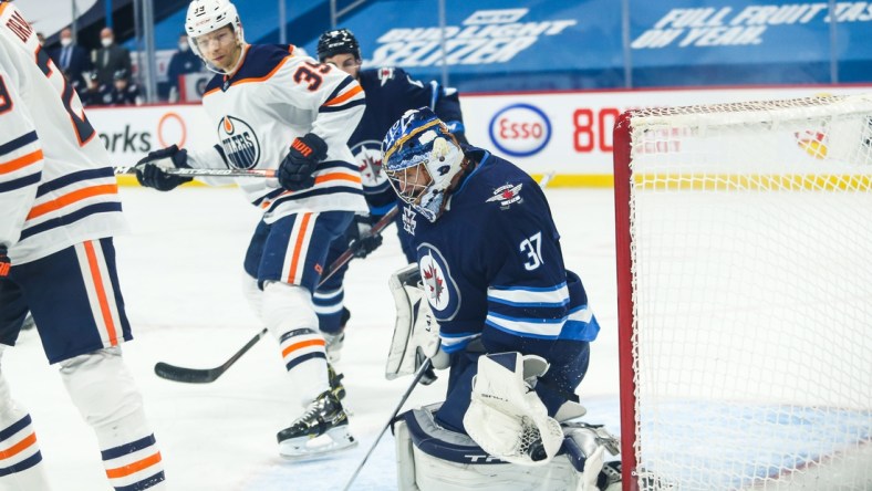 Apr 28, 2021; Winnipeg, Manitoba, CAN;  Winnipeg Jets goalie Connor Hellebuyck (37) makes a save with Edmonton Oilers forward Alex Chiasson (39) looking for a rebound during the first period at Bell MTS Place. Mandatory Credit: Terrence Lee-USA TODAY Sports