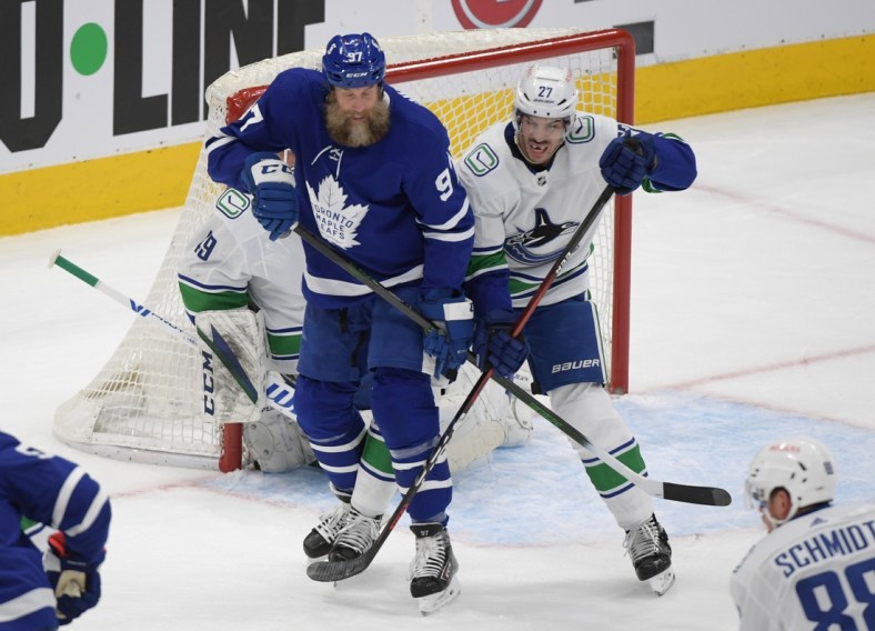 Apr 29, 2021; Toronto, Ontario, CAN;  Toronto Maple Leafs forward Joe Thornton (97) and Vancouver Canucks defenseman Travis Hamonic (27) battle for position in the first period at Scotiabank Arena. Mandatory Credit: Dan Hamilton-USA TODAY Sports