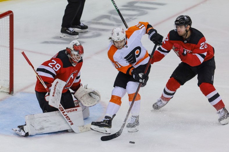 Apr 29, 2021; Newark, New Jersey, USA; Philadelphia Flyers right wing Travis Konecny (11) deflects the puck in front of New Jersey Devils goaltender Mackenzie Blackwood (29) as defenseman Ryan Murray (22) defends during the second period at Prudential Center. Mandatory Credit: Vincent Carchietta-USA TODAY Sports