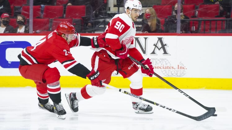 Apr 29, 2021; Raleigh, North Carolina, USA;  Detroit Red Wings center Joe Veleno (90) skates with the puck past Carolina Hurricanes defenseman Brett Pesce (22) during the second period at PNC Arena. Mandatory Credit: James Guillory-USA TODAY Sports