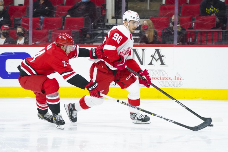 Apr 29, 2021; Raleigh, North Carolina, USA;  Detroit Red Wings center Joe Veleno (90) skates with the puck past Carolina Hurricanes defenseman Brett Pesce (22) during the second period at PNC Arena. Mandatory Credit: James Guillory-USA TODAY Sports