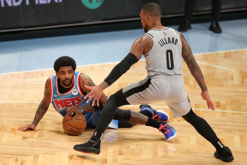 Apr 30, 2021; Brooklyn, New York, USA; Brooklyn Nets point guard Kyrie Irving (11) falls with the ball in front of Portland Trailblazers point guard Damian Lillard (0) during the first quarter at Barclays Center. Mandatory Credit: Brad Penner-USA TODAY Sports