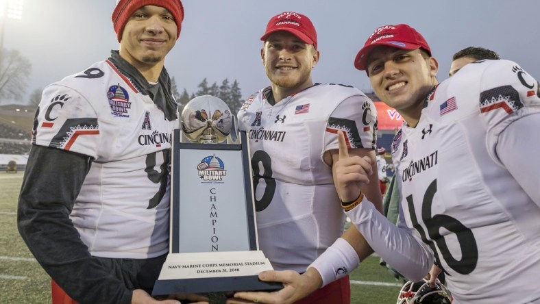 Dec 31, 2018; Annapolis, MD, USA; Cincinnati Bearcats quarterback Desmond Ridder (9) and quarterback Hayden Moore (8) and quarterback John Keller (16) pose with the Military Bowl Championship trophy after the game against the Virginia Tech Hokies at Navy-Marine Corps Memorial Stadium. Mandatory Credit: Scott Taetsch-USA TODAY Sports