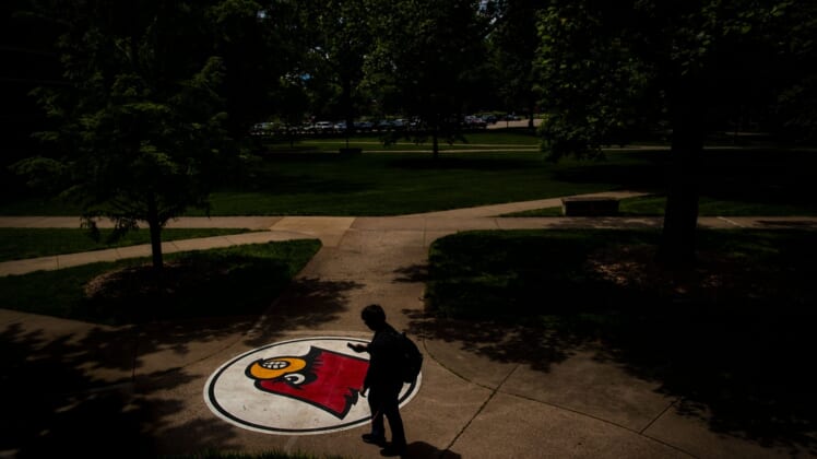 A student looks at his phone as he walks past a cardinal logo Tuesday on the University of Louisville campus. May 14, 2019T9i1125 Uofl Campus
