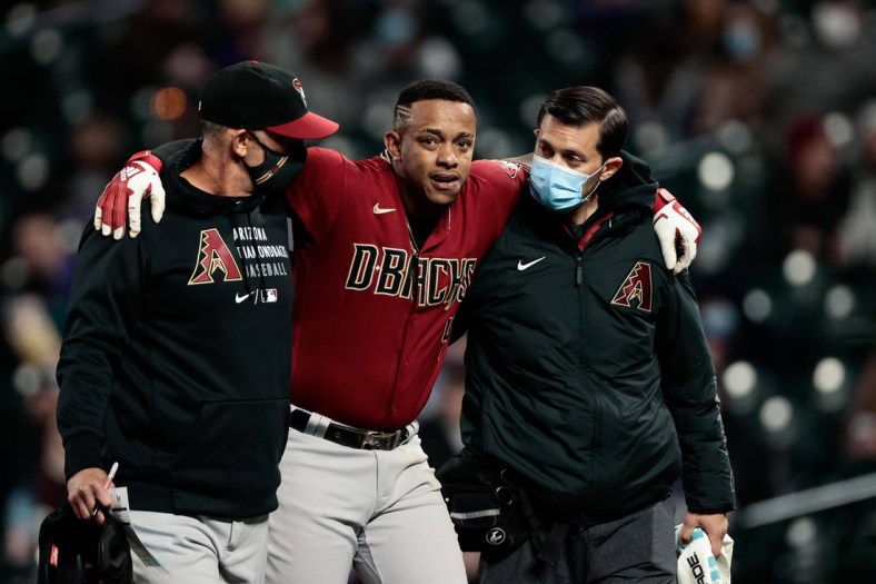Apr 7, 2021; Denver, Colorado, USA; Arizona Diamondbacks center fielder Ketel Marte (4) is helped off the field by quality control/catching coach Robby Hammock (left) and head athletic trainer Ryan DiPanfilo (right) in the fifth inning against the Colorado Rockies at Coors Field. Mandatory Credit: Isaiah J. Downing-USA TODAY Sports